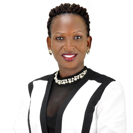 An African woman with short hair, wearing a blazer, smiles at the camera.