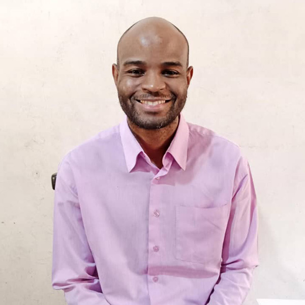 An African man, bald with a slight beard, smiles at the camera.