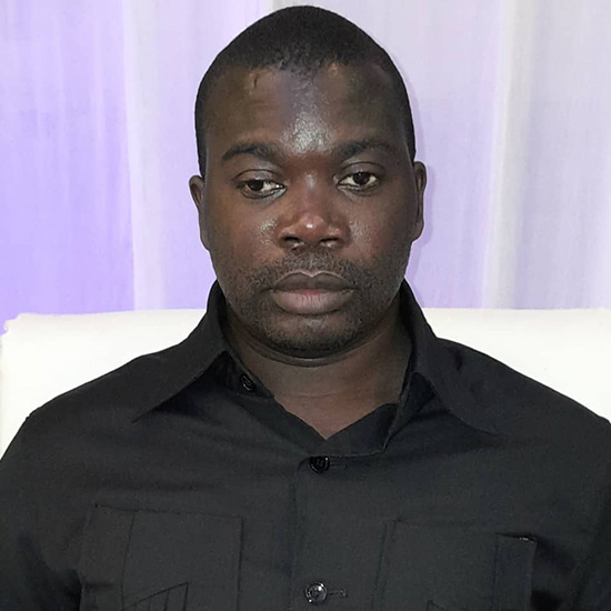 An African man with short hair poses for a photo.