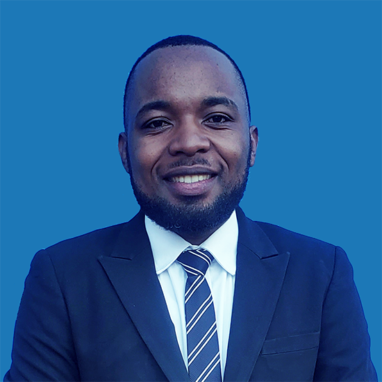 An African man with short hair, wearing a suit and tie, smiles at the camera.