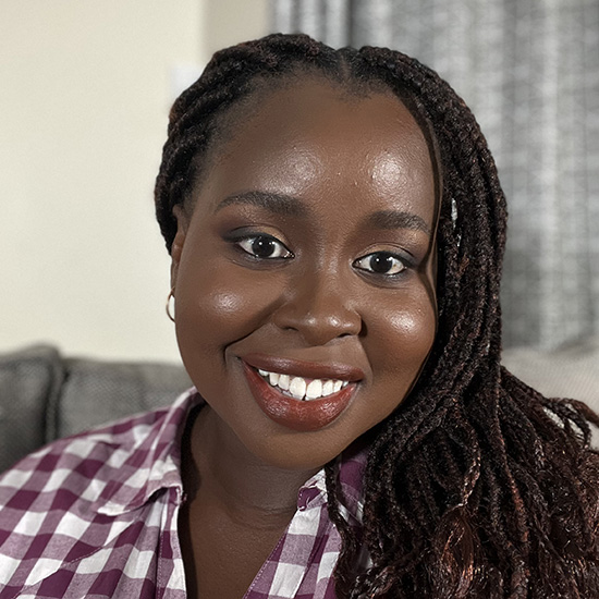 An African woman with long braids smiles at the camera.