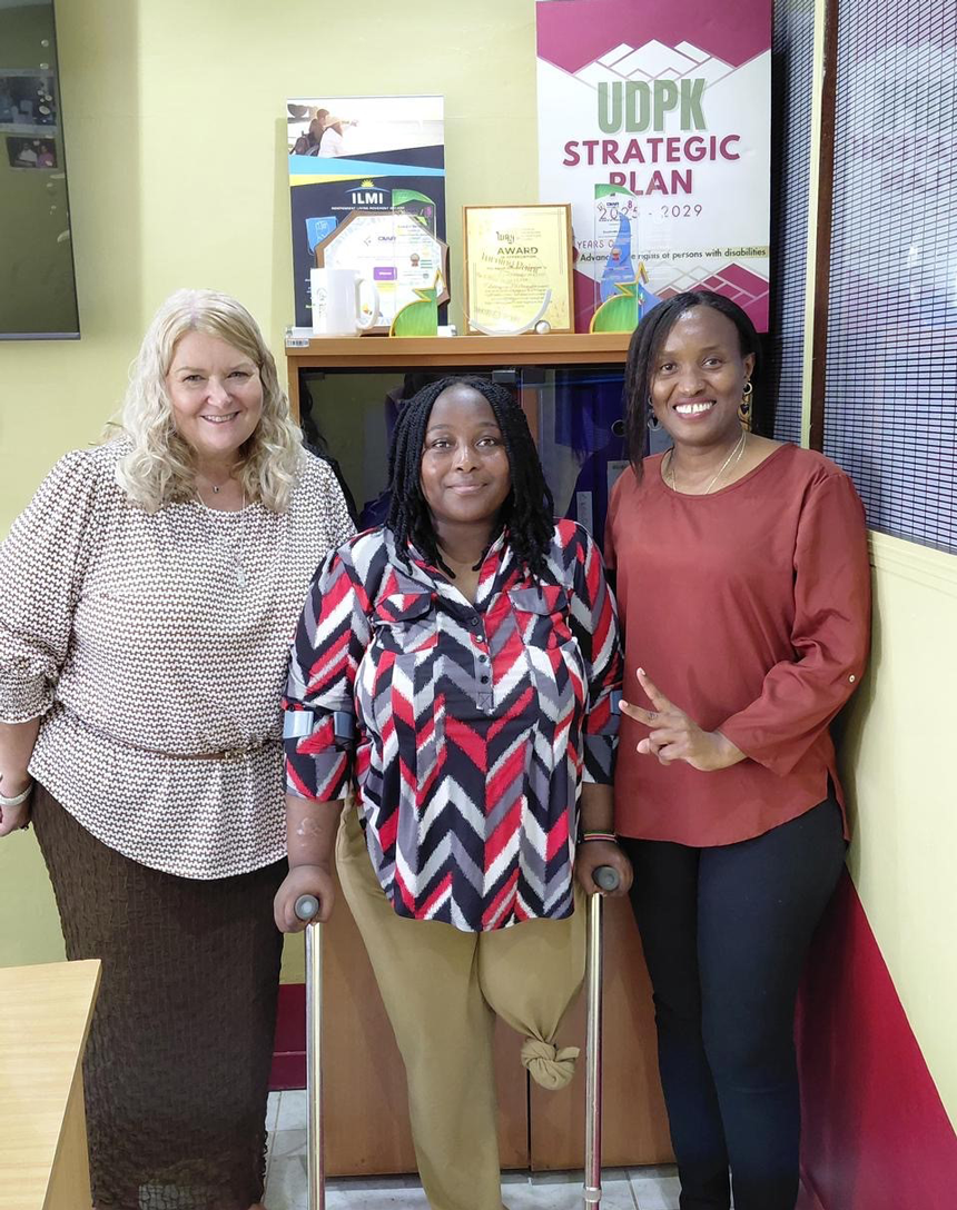 Three women pose for a photo in an office setting.
