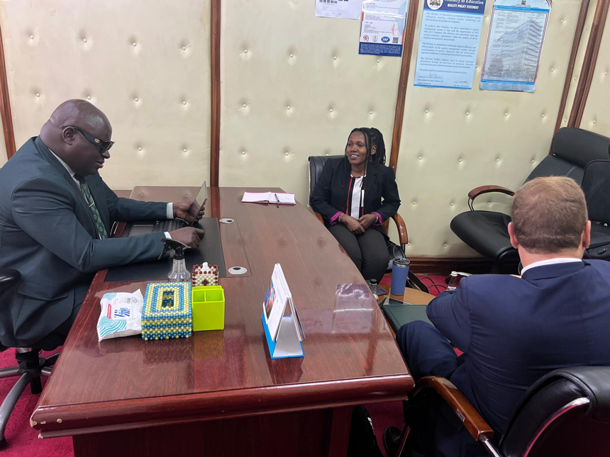 Three individuals—two men and one woman—are seated in an office engaged in conversation.