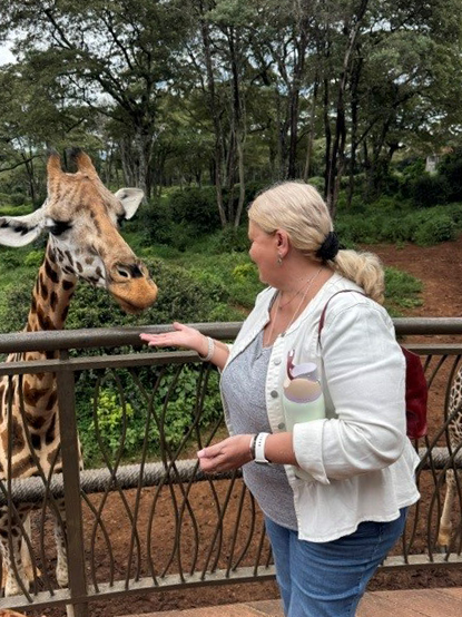 A woman feeds a giraffe at Giraffe Park.