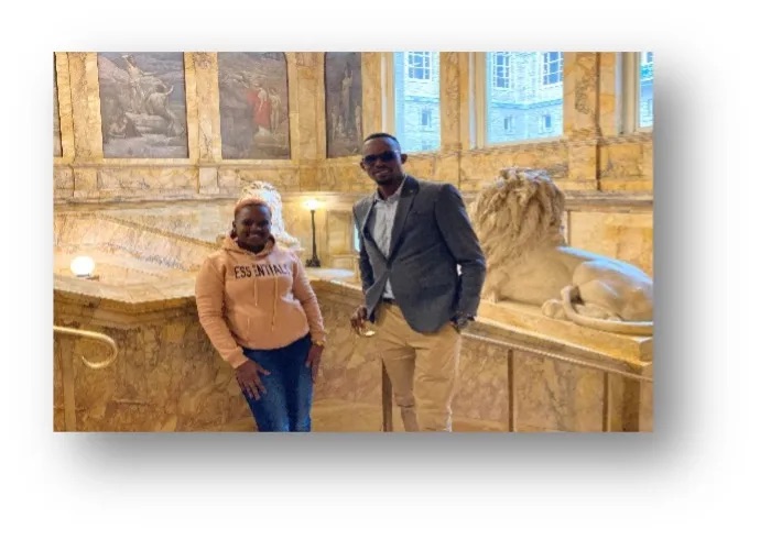 An African woman and an African man stand in front of a large marble room
