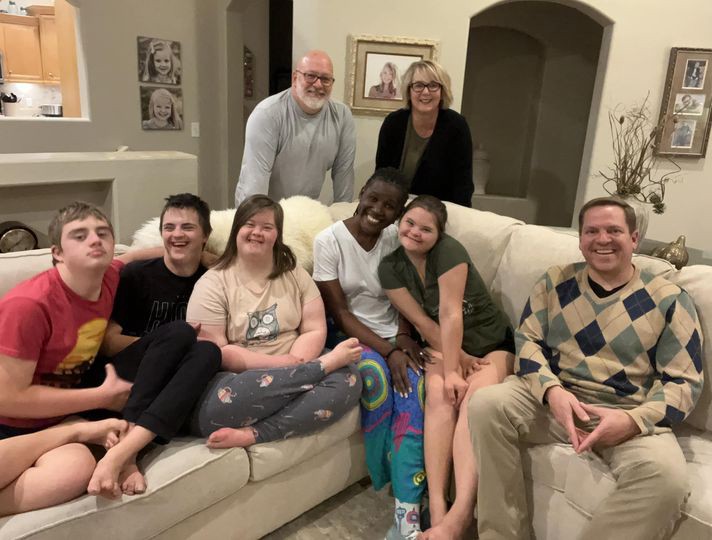 A group of eight people posed around a white couch.