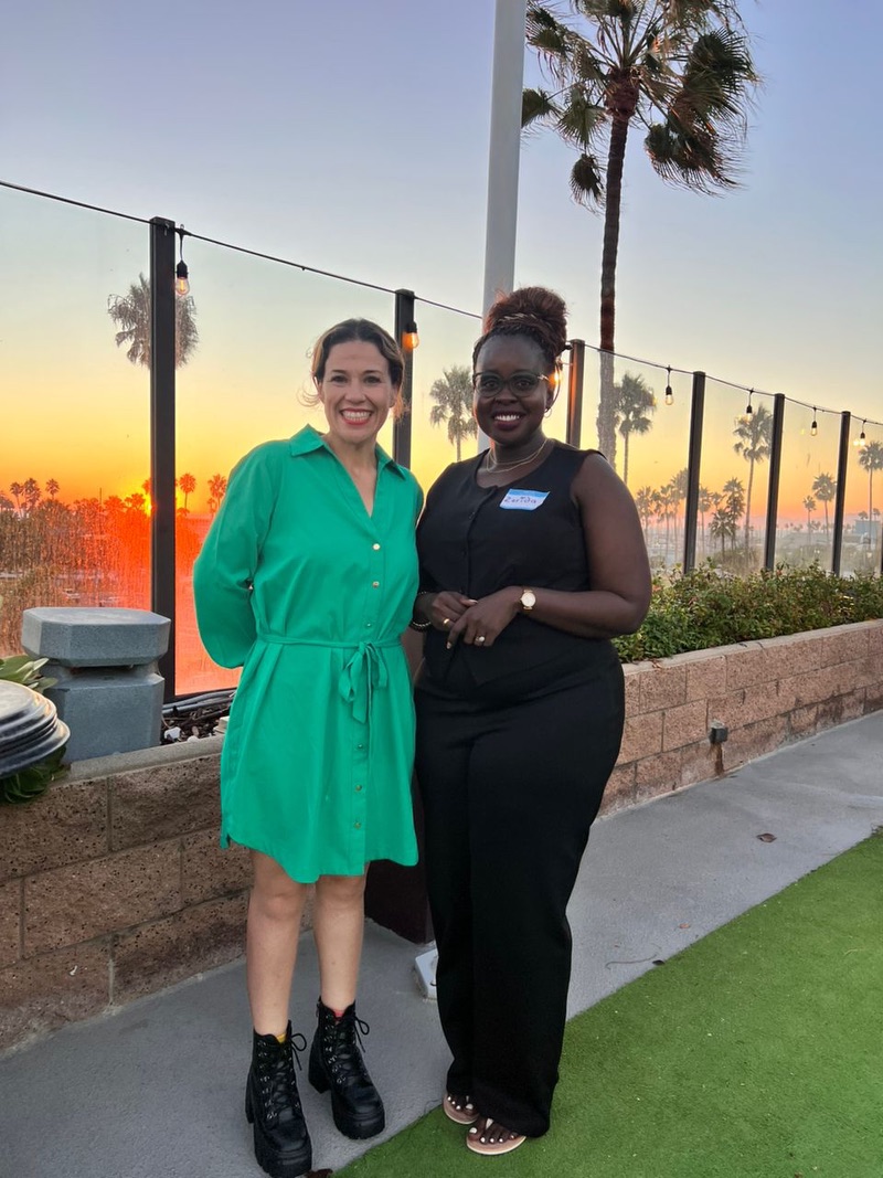 Two women standing next to each other with a sunset behind them