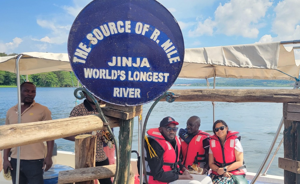 Three people, two Ugandan men and one American woman, on a boat on the river.