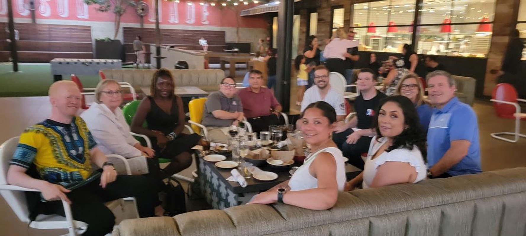 A group of people seated around a table in a restaurant, smiling at the camera for a picture.