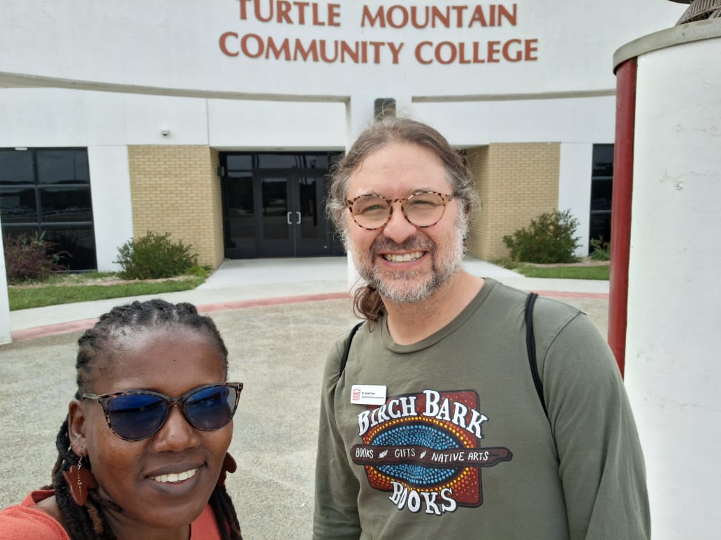 A woman and a man take a selfie in front of a building.  