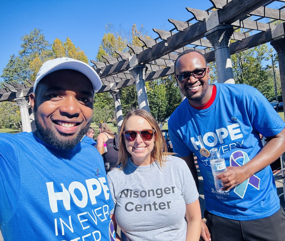 Two men and one woman posing together for a photo outdoors.